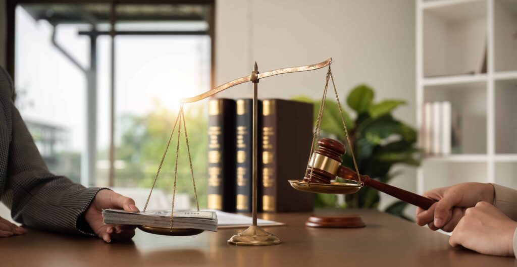 Scales of justice balancing cash and judge&rsquo;s gavel on desk, symbolizing legal corruption, bribery, or financial influence in law