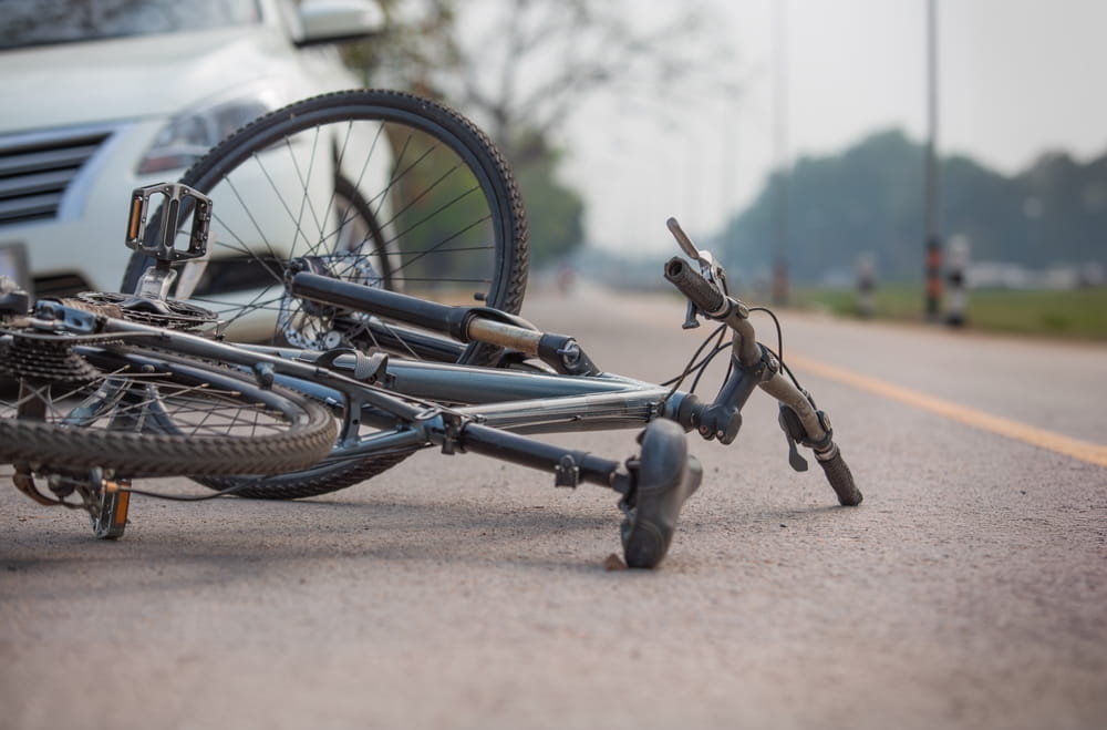 Damaged bicycle lying on the road in front of a car after a collision in Coral Springs FL
