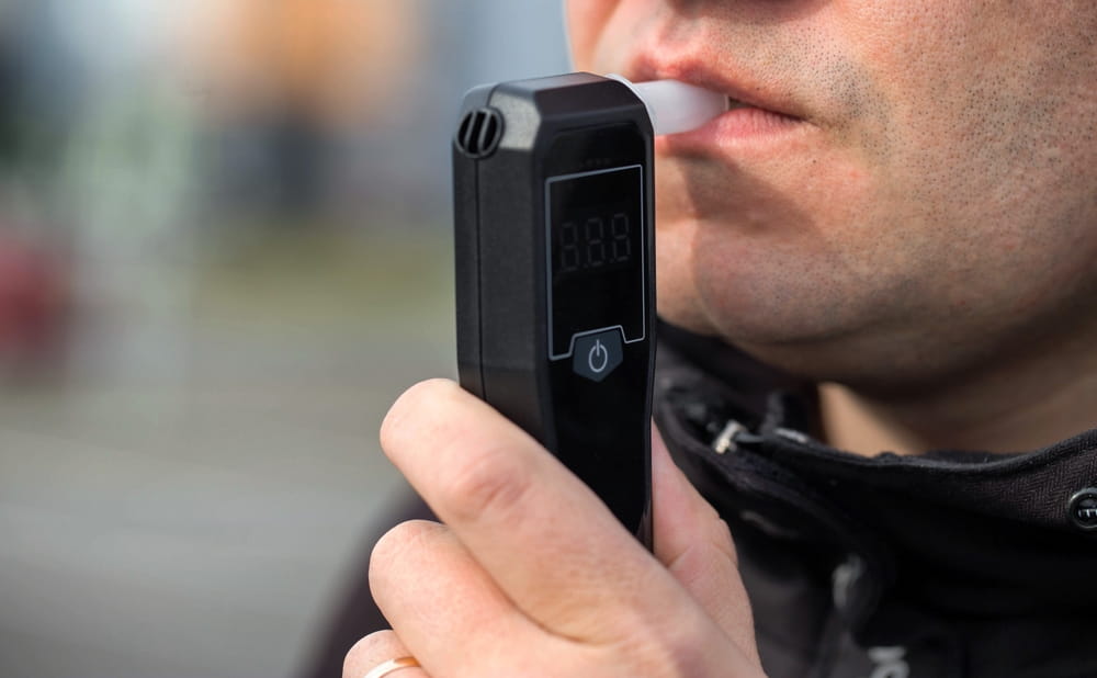 Man blowing into a breathalyzer device during a DUI stop in Coral Springs FL